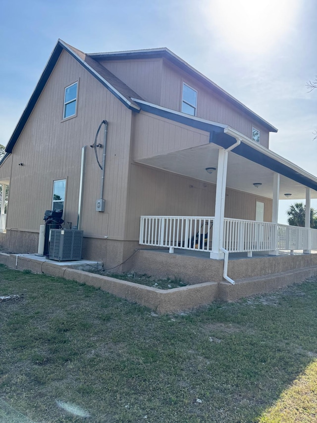 view of side of home with covered porch and a lawn