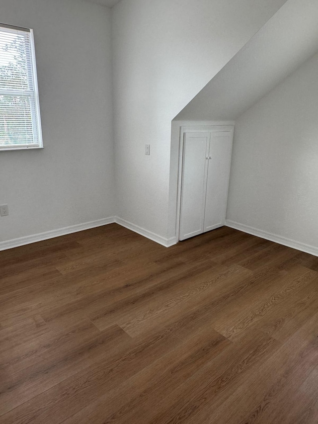 bonus room featuring baseboards and dark wood-style floors