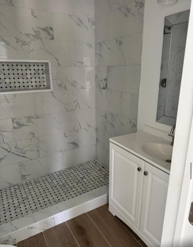 bathroom with vanity, wood finished floors, and a tile shower
