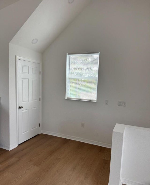 unfurnished bedroom featuring vaulted ceiling, baseboards, and wood finished floors