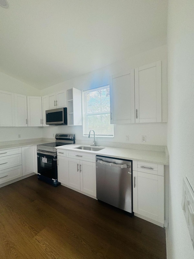 kitchen with a sink, open shelves, white cabinets, appliances with stainless steel finishes, and dark wood-style floors
