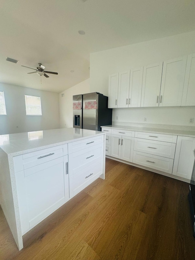 kitchen with stainless steel fridge, white cabinets, visible vents, light countertops, and dark wood-style floors