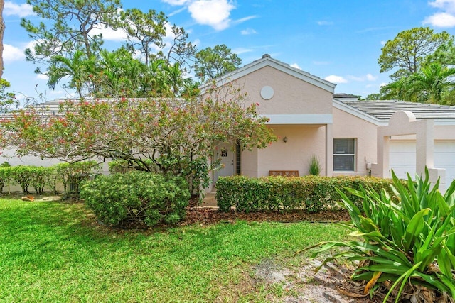view of front of house with an attached garage, a tile roof, stucco siding, and a front lawn
