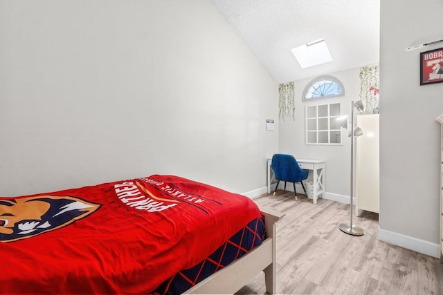 bedroom with wood finished floors, baseboards, and lofted ceiling with skylight