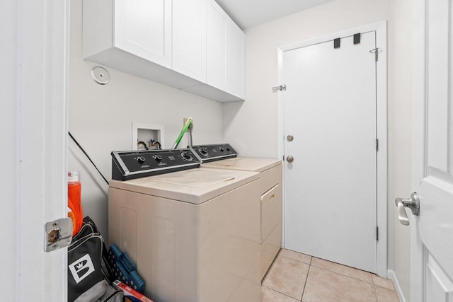 laundry area featuring light tile patterned floors, washing machine and clothes dryer, and cabinet space
