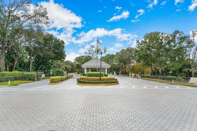 view of road featuring curbs, a gated entry, and street lights