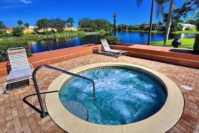 view of pool with a water view, an in ground hot tub, and a patio