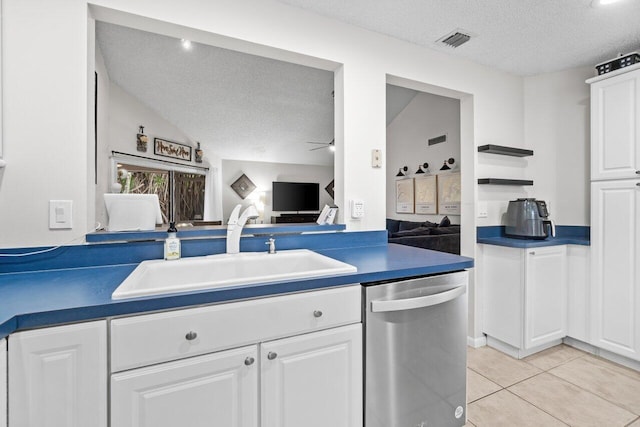 kitchen featuring stainless steel dishwasher, a textured ceiling, a sink, and dark countertops