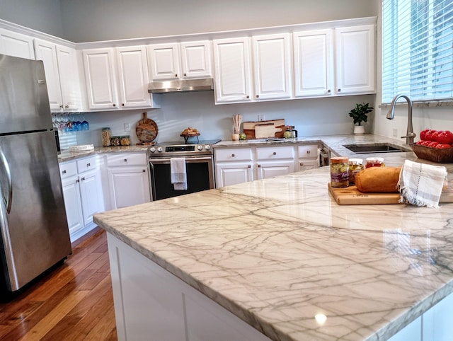 kitchen with a sink, light wood-style floors, stainless steel appliances, white cabinetry, and under cabinet range hood