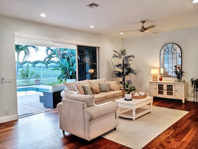 living room with a healthy amount of sunlight, a ceiling fan, dark wood finished floors, and visible vents