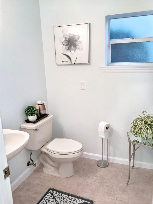 half bath with tile patterned flooring, baseboards, and toilet