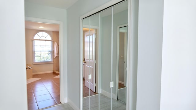 hallway featuring light tile patterned flooring and baseboards