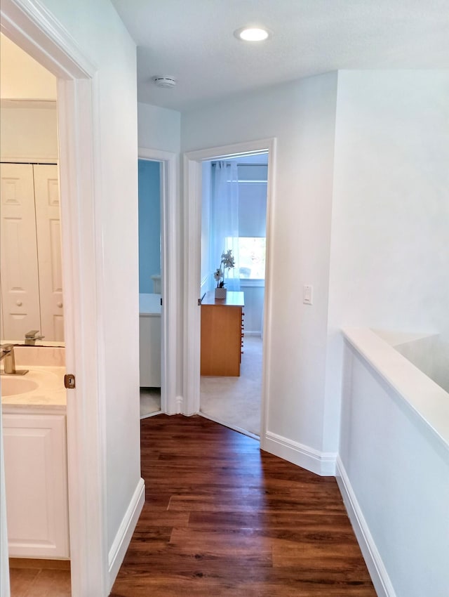 corridor with a sink, baseboards, recessed lighting, and wood finished floors