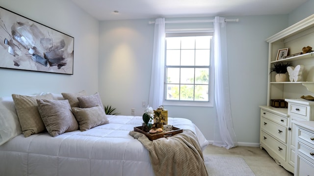 bedroom featuring baseboards, light carpet, and multiple windows