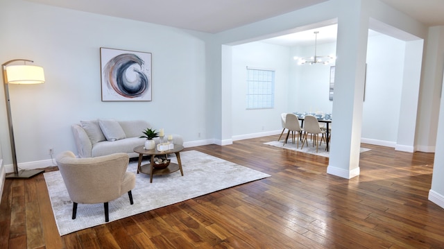 living room featuring baseboards, dark wood finished floors, and a notable chandelier