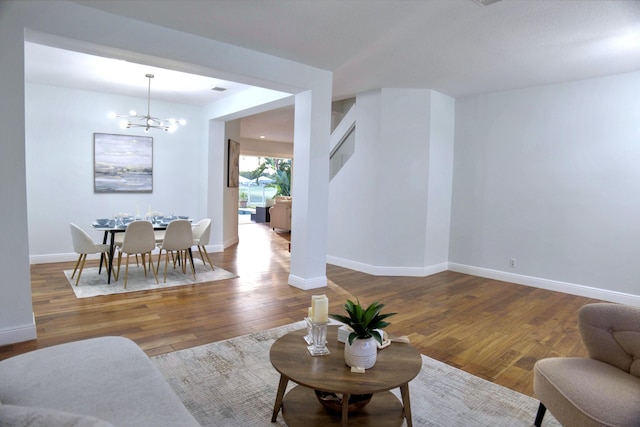 living room featuring baseboards, an inviting chandelier, and wood finished floors