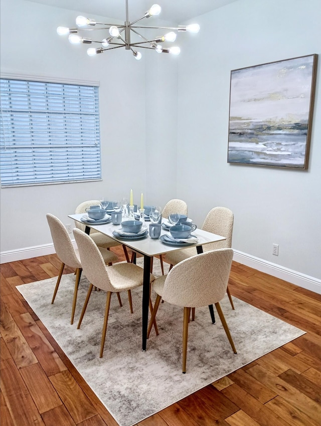 dining room featuring baseboards, wood finished floors, and a notable chandelier