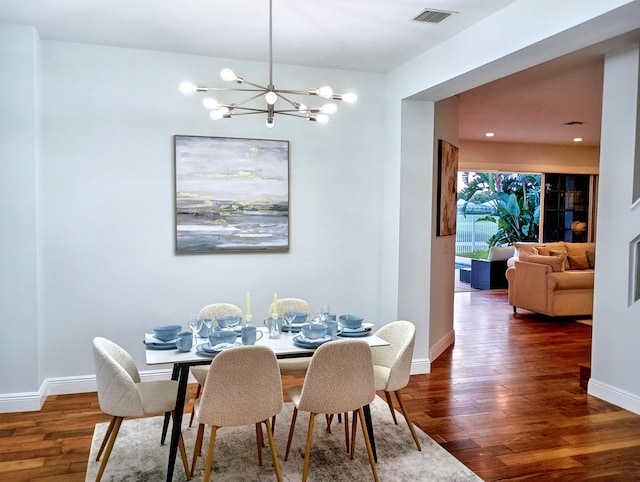 dining room featuring baseboards, visible vents, wood finished floors, and an inviting chandelier