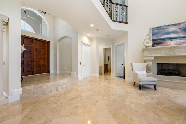 712 NE 71st St, Boca Raton, FL 33487 - entrance foyer featuring arched walkways, a towering ceiling, a fireplace with raised hearth, marble finish floor, and baseboards