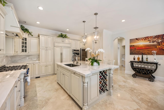 712 NE 71st St, Boca Raton, FL 33487 - kitchen featuring arched walkways, a sink, a center island with sink, light stone counters, and ornamental molding