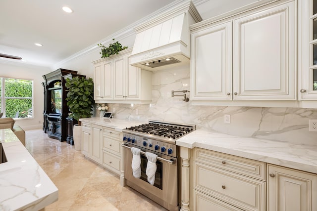 712 NE 71st St, Boca Raton, FL 33487 - kitchen with high end stainless steel range, cream cabinets, premium range hood, backsplash, and light stone countertops
