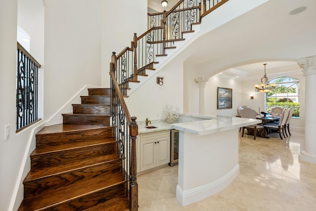 712 NE 71st St, Boca Raton, FL 33487 - stairway featuring a towering ceiling, an inviting chandelier, crown molding, decorative columns, and arched walkways