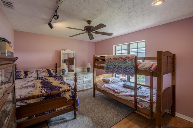 bedroom featuring a textured ceiling, wood finished floors, ceiling fan, and visible vents
