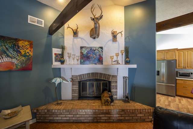 living area with a fireplace, beam ceiling, a toaster, and visible vents