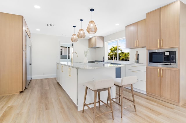 841 SE 5th Ter, Pompano Beach, FL 33060 - kitchen with a sink, built in microwave, light wood finished floors, a center island with sink, and visible vents