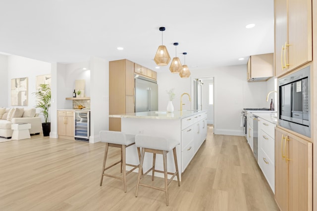 841 SE 5th Ter, Pompano Beach, FL 33060 - kitchen featuring an island with sink, a kitchen breakfast bar, wine cooler, light wood-style floors, and built in appliances