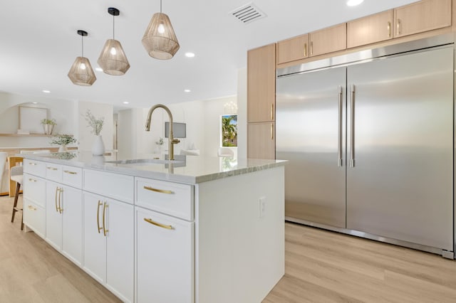 841 SE 5th Ter, Pompano Beach, FL 33060 - kitchen featuring built in refrigerator, a sink, light wood finished floors, light stone countertops, and visible vents