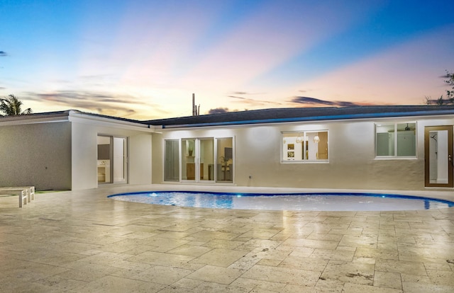 841 SE 5th Ter, Pompano Beach, FL 33060 - back of house at dusk with stucco siding, an outdoor pool, and a patio