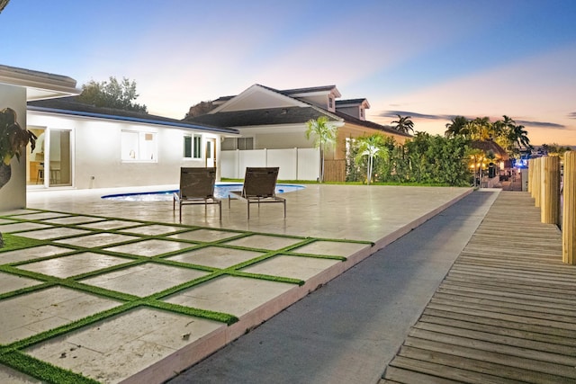 841 SE 5th Ter, Pompano Beach, FL 33060 - back of property at dusk featuring fence, a patio area, a fenced in pool, and stucco siding