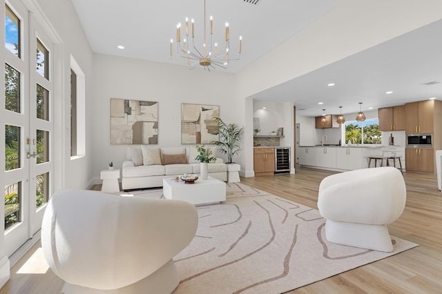 841 SE 5th Ter, Pompano Beach, FL 33060 - living room featuring wine cooler, french doors, light wood-style flooring, recessed lighting, and a notable chandelier