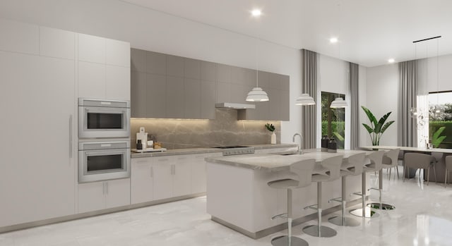 kitchen with backsplash, a sink, a center island with sink, and plenty of natural light