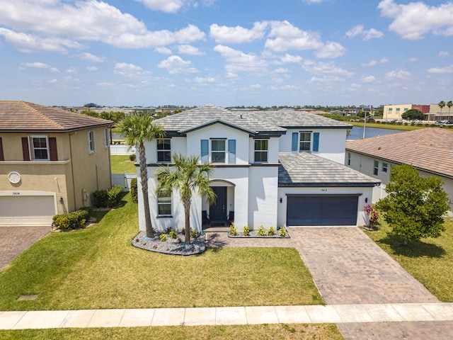 view of front facade with stucco siding, a front lawn, decorative driveway, and an attached garage