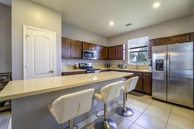 kitchen featuring recessed lighting, a breakfast bar, visible vents, a sink, and appliances with stainless steel finishes