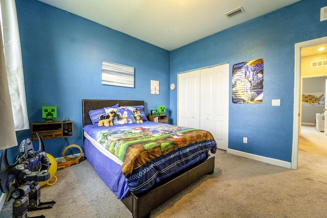carpeted bedroom with a closet, a textured wall, visible vents, and baseboards