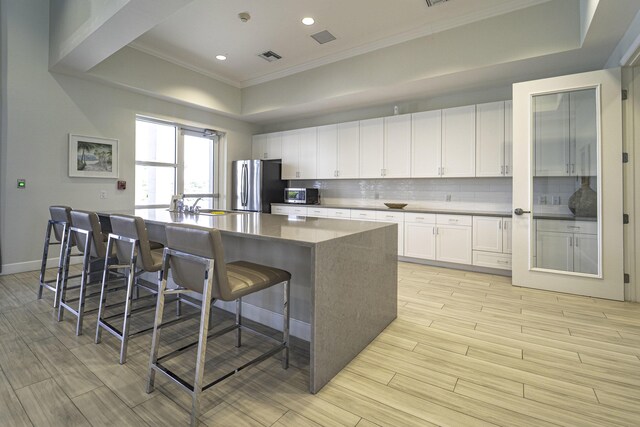 kitchen with appliances with stainless steel finishes, tasteful backsplash, crown molding, and light wood-type flooring