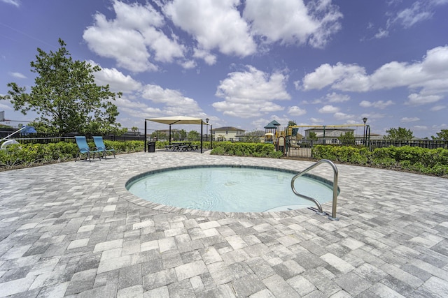 view of swimming pool featuring a swimming pool, a patio, fence, and playground community