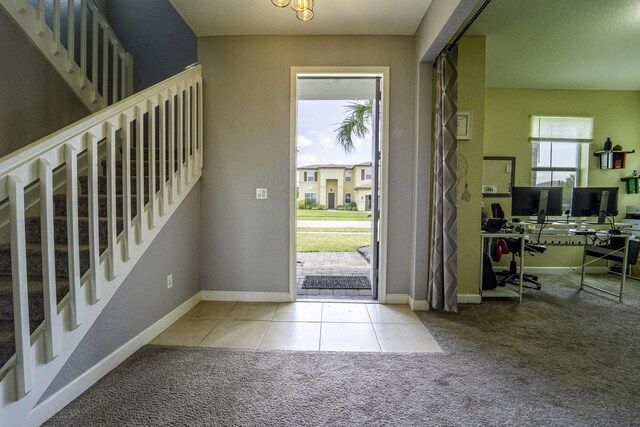 foyer entrance featuring tile patterned flooring, baseboards, carpet flooring, and stairs