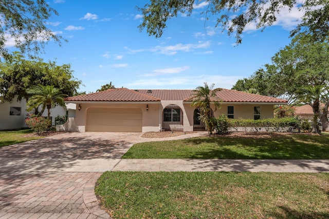 mediterranean / spanish-style house with a front lawn, a tiled roof, driveway, a garage, and stucco siding
