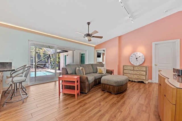 living room with rail lighting, lofted ceiling, a ceiling fan, and light wood-type flooring