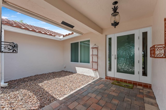 entrance to property with french doors, a tile roof, and stucco siding