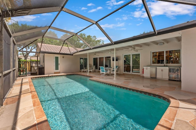 pool featuring a patio area, glass enclosure, a ceiling fan, a sink, and area for grilling