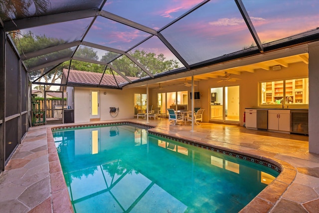 outdoor pool with a patio area, a lanai, a ceiling fan, and exterior kitchen