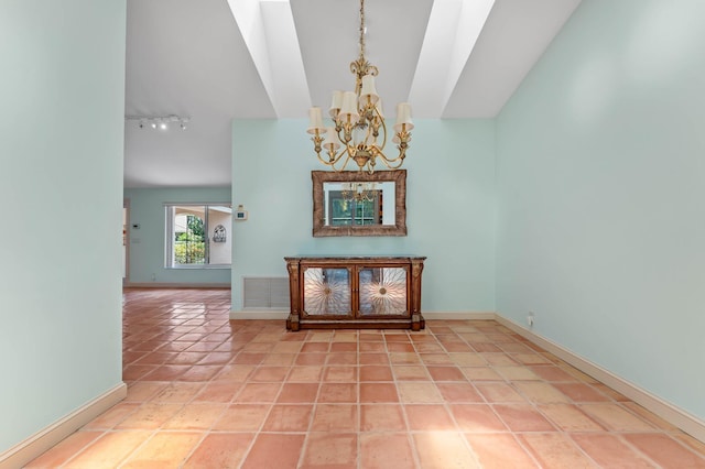 interior space with vaulted ceiling, baseboards, rail lighting, and a chandelier