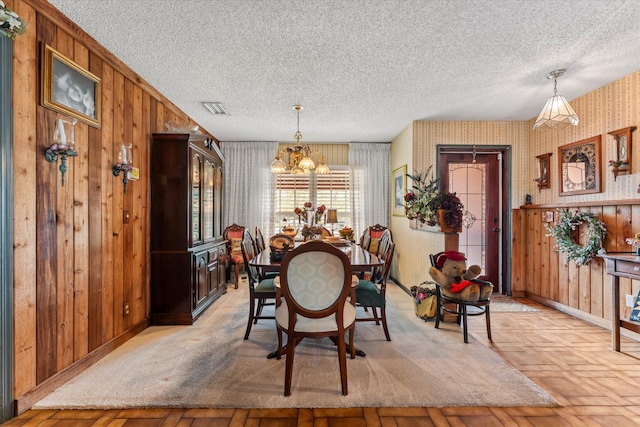 dining area with a notable chandelier, wallpapered walls, a textured ceiling, baseboards, and visible vents