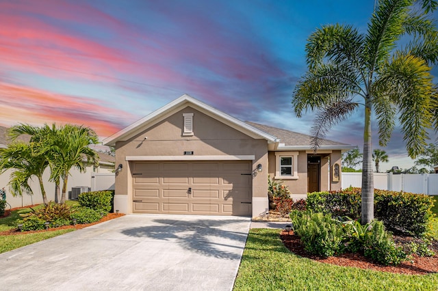 ranch-style home featuring concrete driveway, an attached garage, fence, and stucco siding