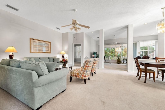 5166 SE Inkwood Way, Hobe Sound, FL 33455 - living area featuring visible vents, a textured ceiling, light colored carpet, and ceiling fan with notable chandelier